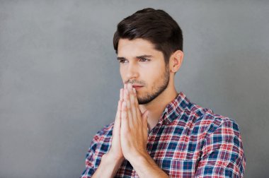 Thoughtful man holding hands clasped