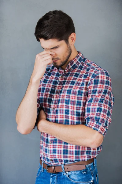 Frustrated young man massaging his nose — Stock Photo, Image