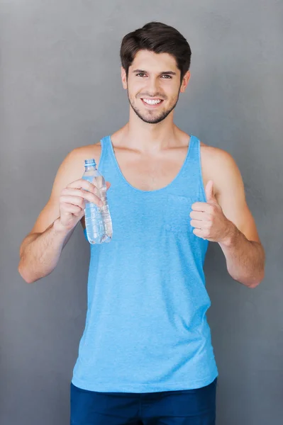 Man holding bottle with water and thumb up — Stock Photo, Image