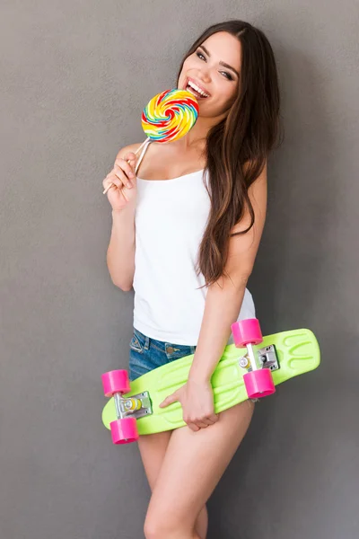Woman eating lollipop and holding skateboard — Zdjęcie stockowe