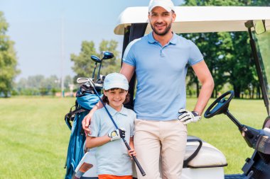 man embracing his son while leaning golf cart