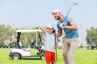 man embracing his son on  golf course