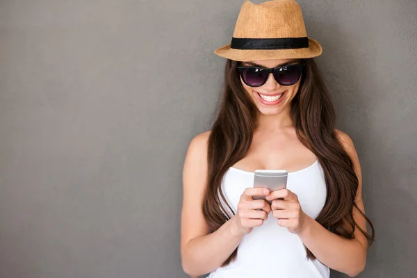 Woman holding mobile phone and smiling — Stock Photo, Image