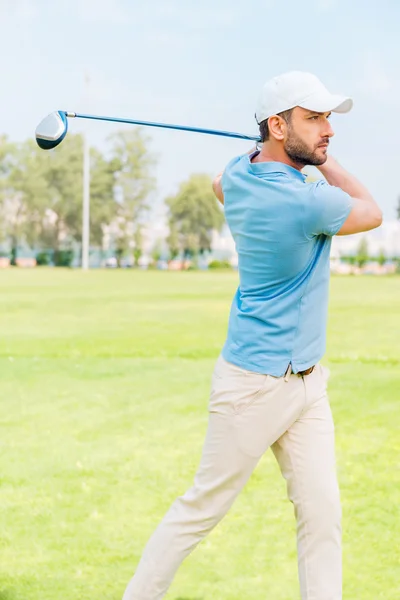 Уверенный молодой человек играет в гольф — стоковое фото