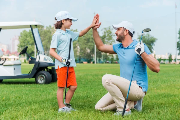 Hombre e hijo dando choca cinco en el campo de golf —  Fotos de Stock