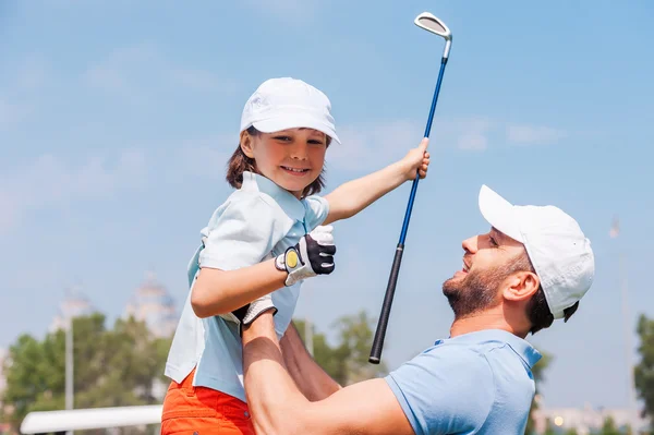 Man picking up his son on golf course — 스톡 사진