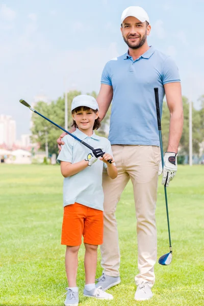 Man embracing his son on golf course — 图库照片