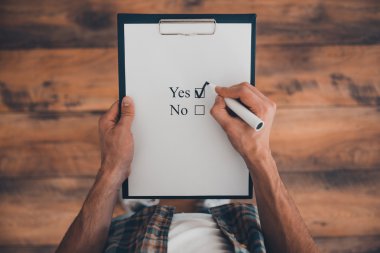 man making check mark in clipboard