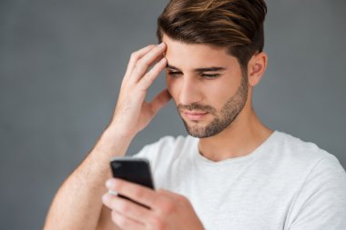 Depressed man looking at his mobile phone