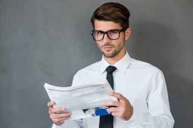 man in shirt and tie holding newspaper