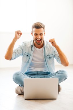 Excited young man working at laptop