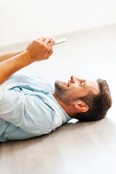 Man holding mobile phone lying on floor — Stockfoto