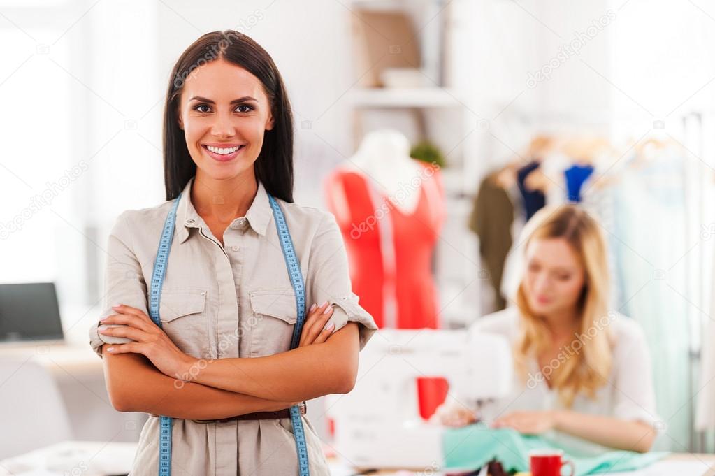 woman keeping arms crossed and  another woman sewing