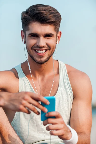 Man in headphones holding smart phone — Stock Photo, Image