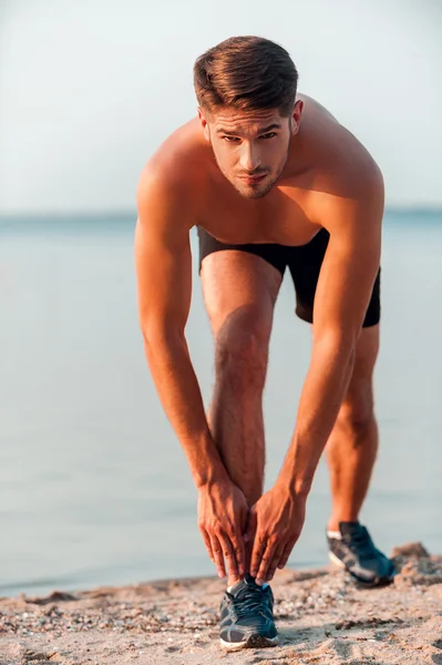 Muscular man stretching body before running — Stock Photo, Image
