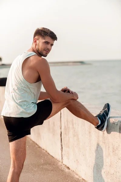 Homem muscular alongamento pernas antes de correr — Fotografia de Stock