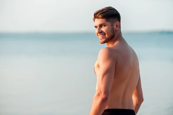 Muscular man standing at seaside — Stock Photo, Image