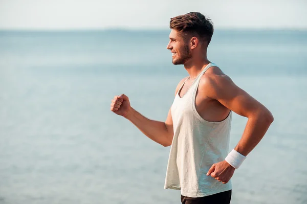 Musculoso hombre corriendo por la orilla del río — Foto de Stock