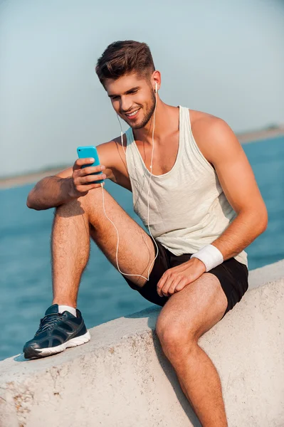 Man in headphones holding smart phone — Stock Photo, Image