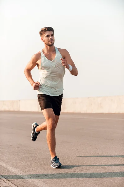 Homem muscular correndo ao longo da estrada — Fotografia de Stock
