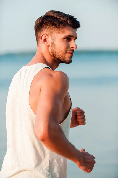 Muscular man running along seaside — Stock Photo, Image