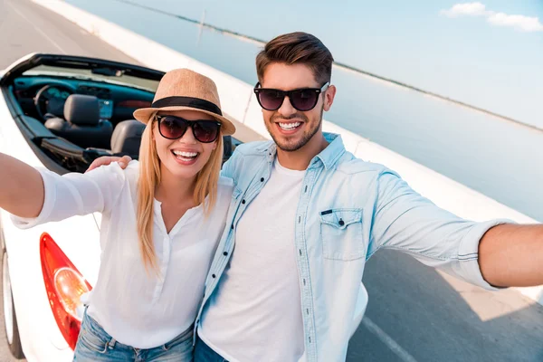 Coppia facendo selfie vicino convertibile — Foto Stock