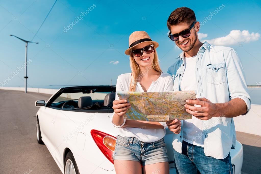 couple examining map near convertible