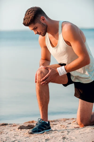 Hombre muscular masajeando rodilla antes de correr —  Fotos de Stock