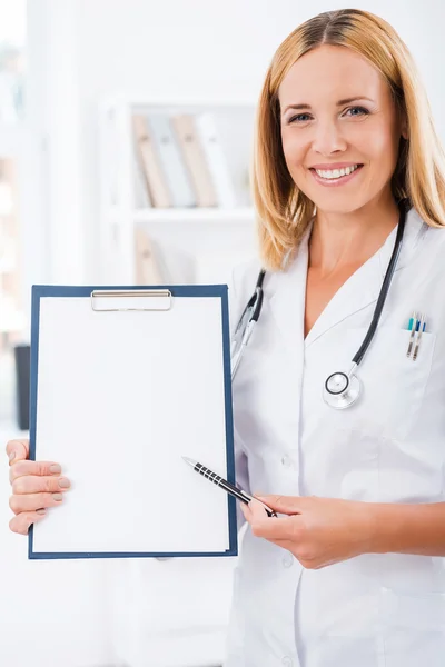 Doctor in uniform pointing at clipboard — Stock Photo, Image