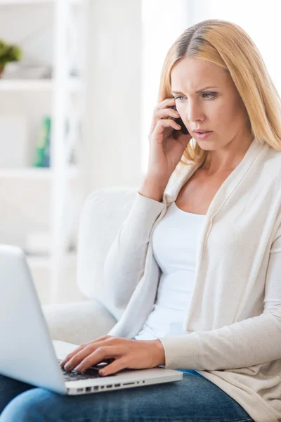 Vrouw praten over telefoon en die op laptop werkt — Stockfoto