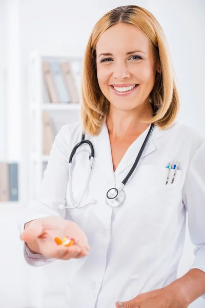 Arzt in Uniform hält bunte Pillen in der Hand — Stockfoto