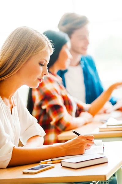 Kvinnan skriver i anteckningsblock i klassrummet — Stockfoto