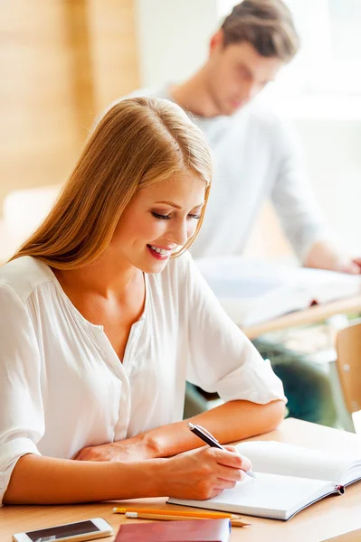 Kvinnan skriver i anteckningsblock i klassrummet — Stockfoto