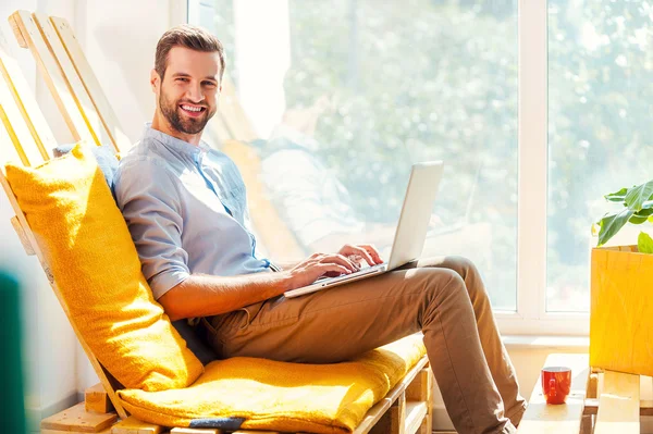 Jovem sorridente trabalhando no laptop — Fotografia de Stock