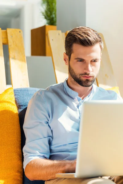 Jeune homme concentré travaillant sur un ordinateur portable — Photo