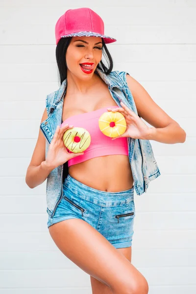 Woman holding donuts against her breast — Stock Photo, Image