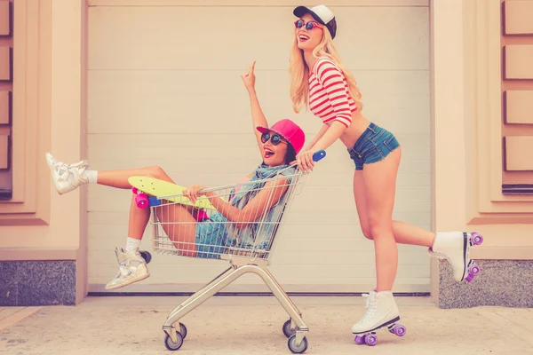 Woman carrying her friend in shopping cart — Stock Photo, Image