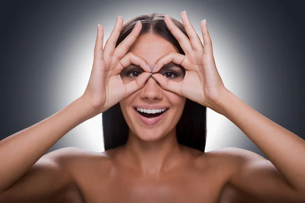 Woman looking at camera through fingers — Stock Photo, Image