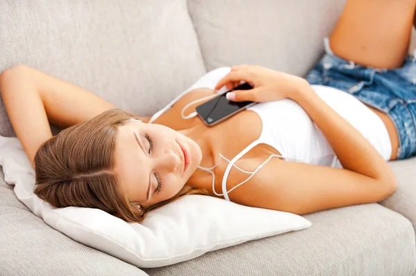 Woman in headphones lying on sofa — Stock Photo, Image