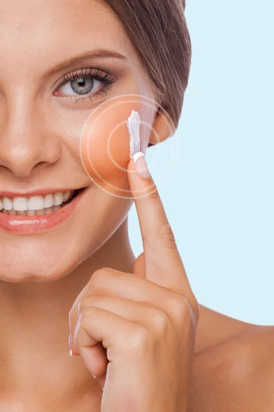 Woman spreading cream on her face — Stock Photo, Image