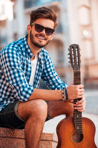 Sorridente giovane uomo che tiene la chitarra — Foto Stock