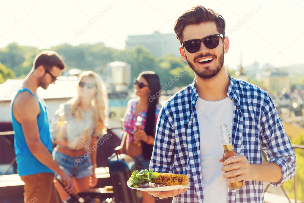 man holding beer and plate with food