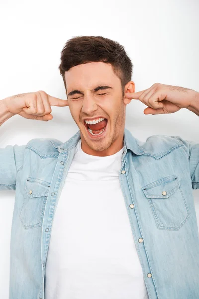 Frustrated young man holding fingers in ears — Stock Photo, Image