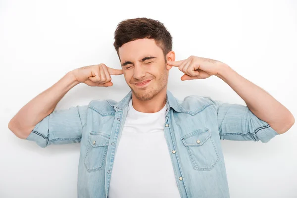 Frustrated young man holding fingers in ears — Stock Photo, Image