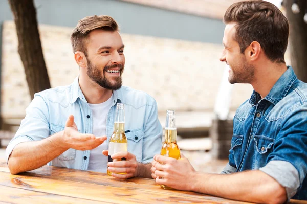 Homens conversando e segurando garrafas com cerveja — Fotografia de Stock