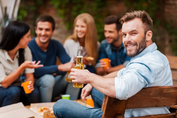 Homem segurando garrafa com cerveja com amigos — Fotografia de Stock