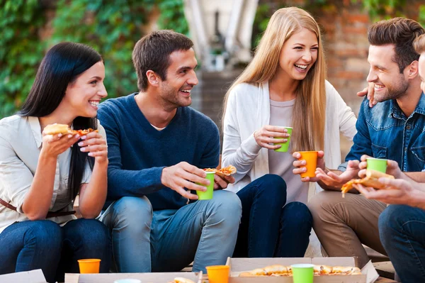 cheerful people talking and eating pizza