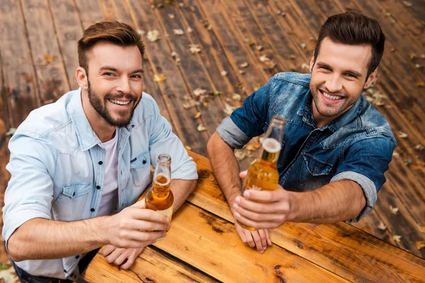 Young men stretching out bottles with beer — Stock Photo, Image