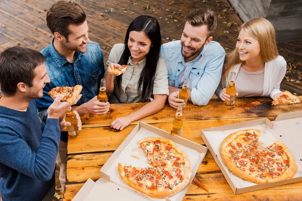 Gente sosteniendo cerveza y comiendo pizza — Foto de Stock