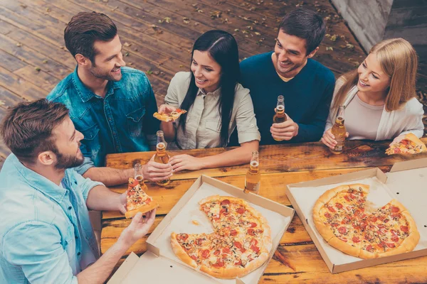 Gente sosteniendo cerveza y comiendo pizza —  Fotos de Stock